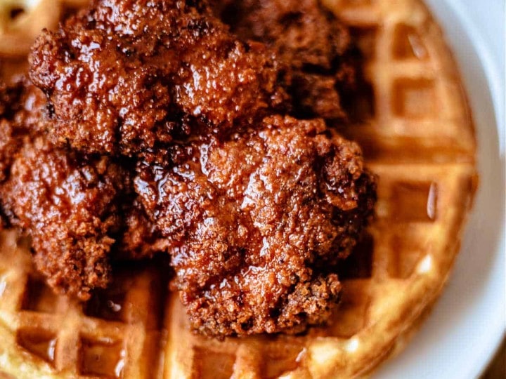 chicken and waffles with honey sriracha on a white plate