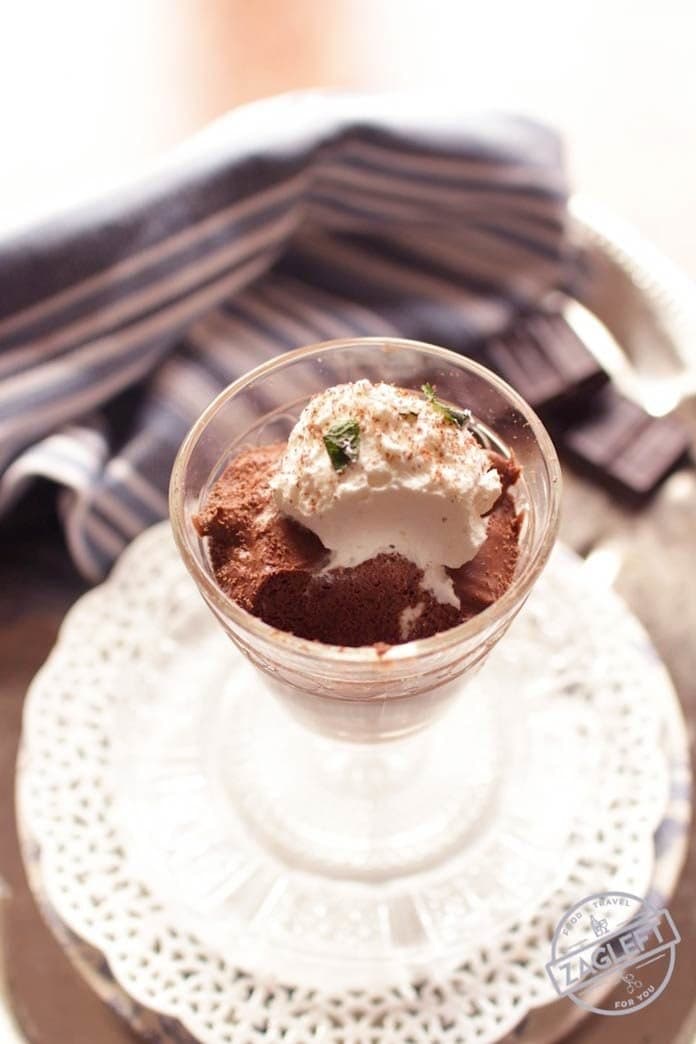 Spoonful missing from chocolate mousse in a dessert glass topped with whipped cream