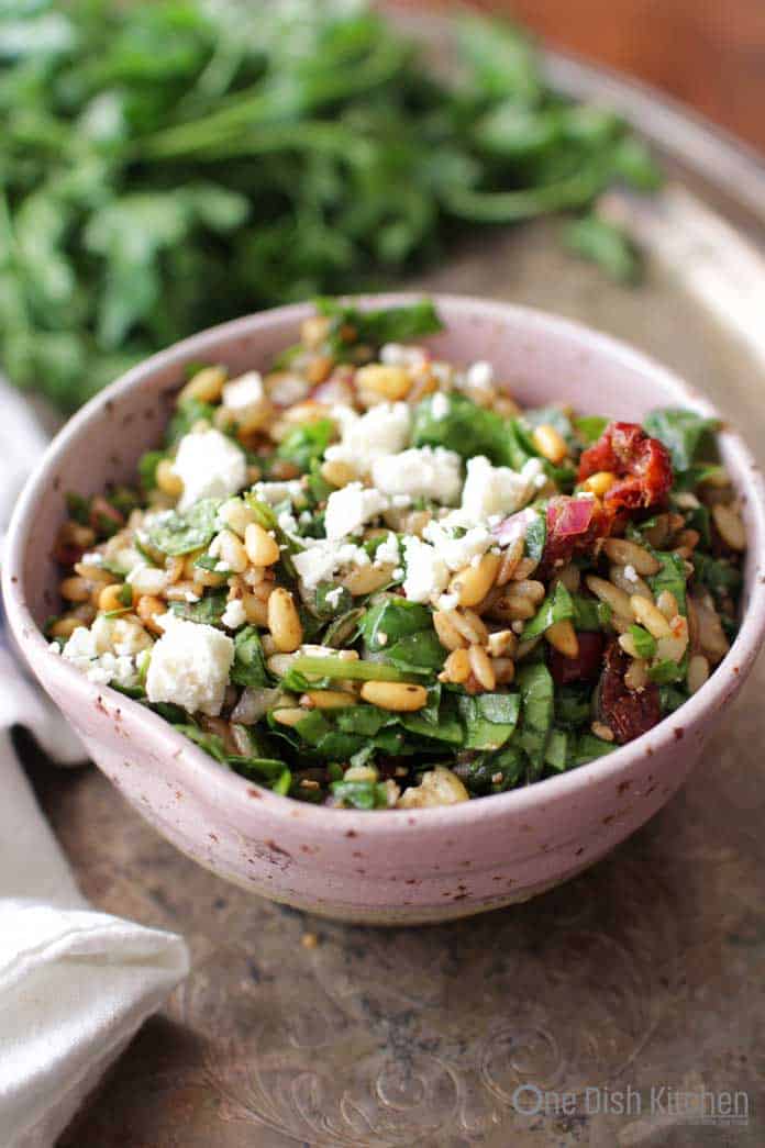 a close up of a spinach and orzo salad in a bowl on a silver tray | one dish kitchen