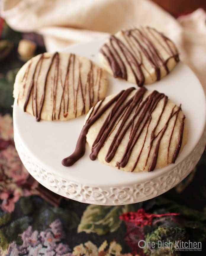 A plate of three shortbread cookies drizzled with melted chocolate