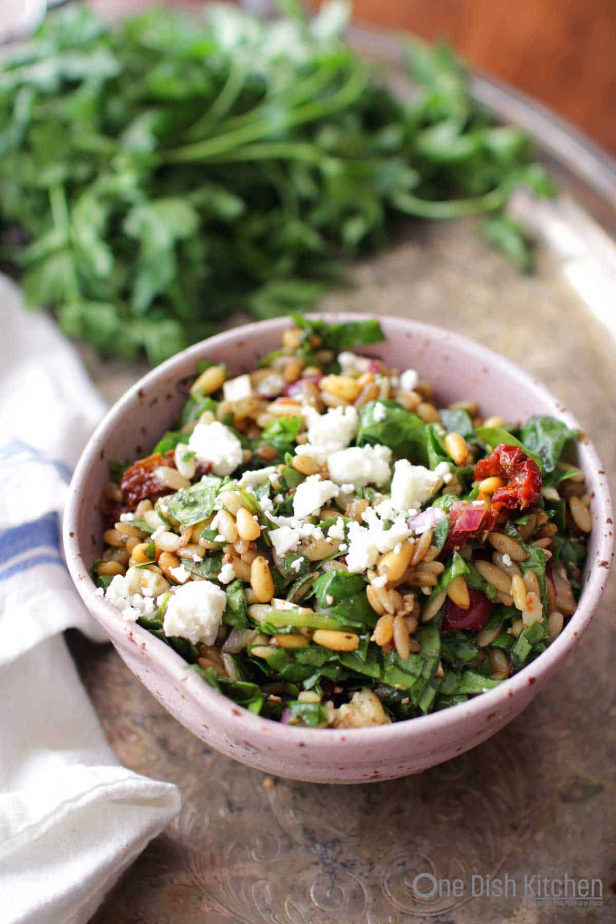 a salad filled with spinach and orzo and topped with feta cheese | one dish kitchen