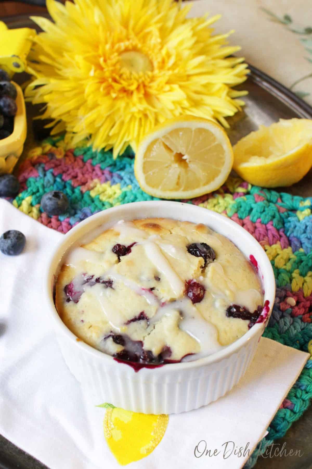 a lemon blueberry muffin on a tray surrounded by blueberries and lemons.