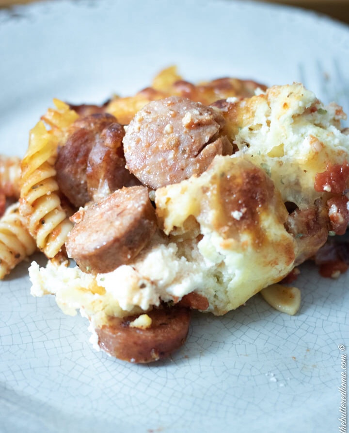 close up of baked sausage pasta on a grey plate