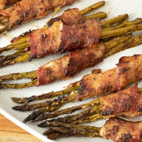 baked bacon wrapped asparagus on a gray plate