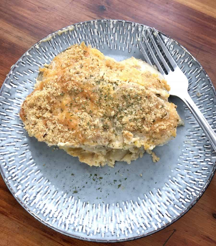 Scalloped potatoes and onions ona blue plate with a silver fork.