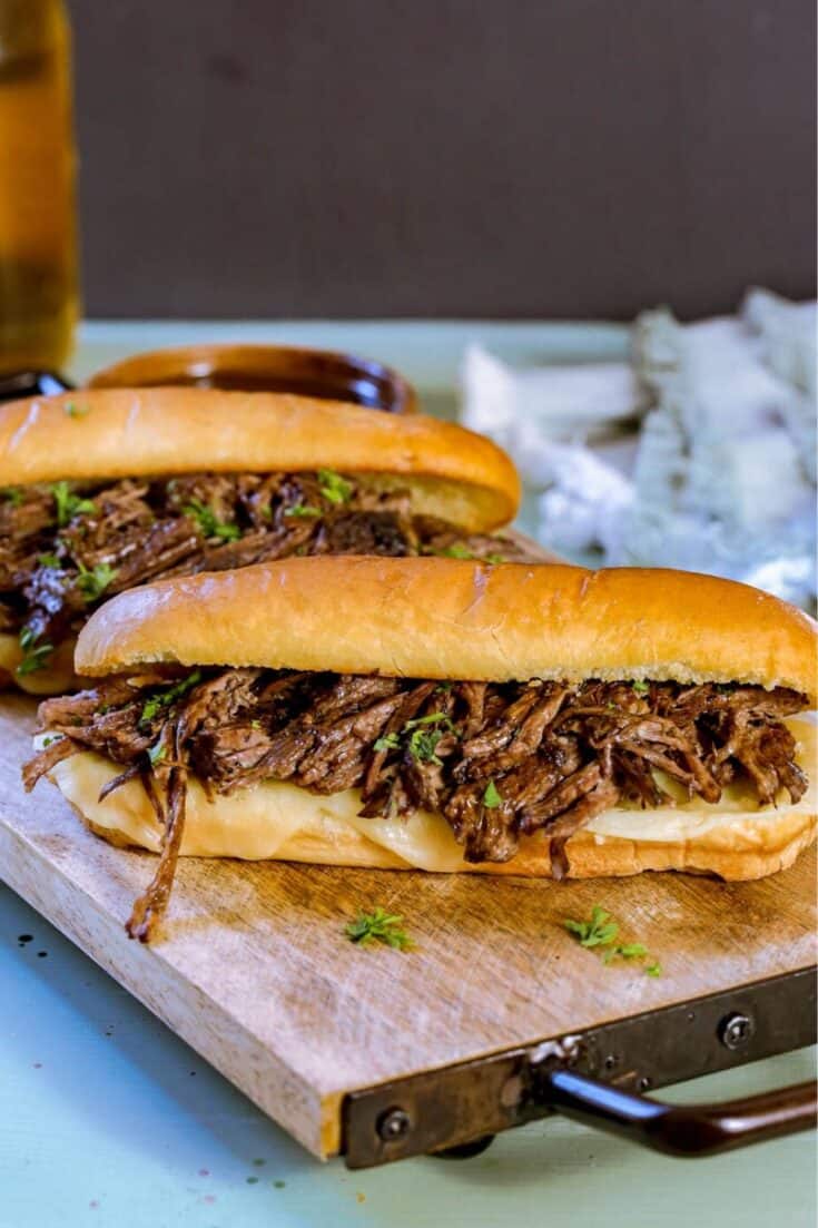 These flavorful Easy Crock Pot French Dip Sandwiches are a family favorite. Top them with provolone cheese and serve with a side of au jus. This Slow Cooker French Dip Sandwich recipe is perfect for a weeknight meal or to serve at a game day party or casual get together. This is an easy sandwich recipe that everyone will enjoy. #frenchdip #slowcookerrecipe #crockpotrecipe #slowcookerfrenchdip