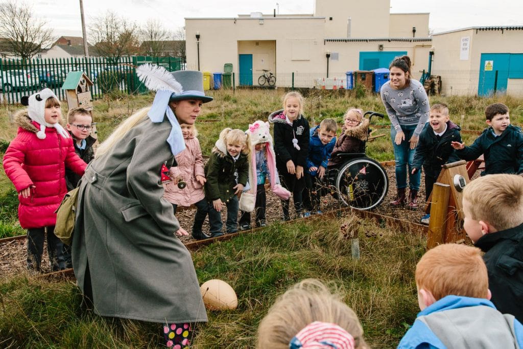 A woman dressed in costume and surrounded by school children.