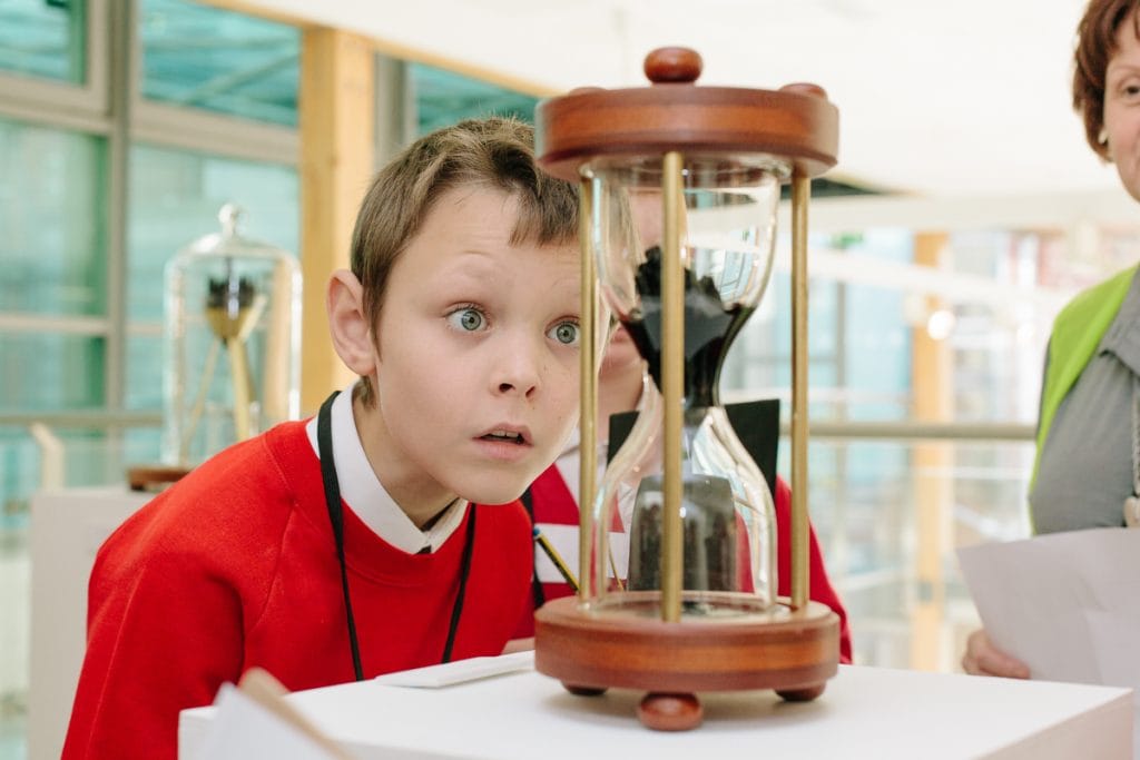 A boy staring at an hourglass.