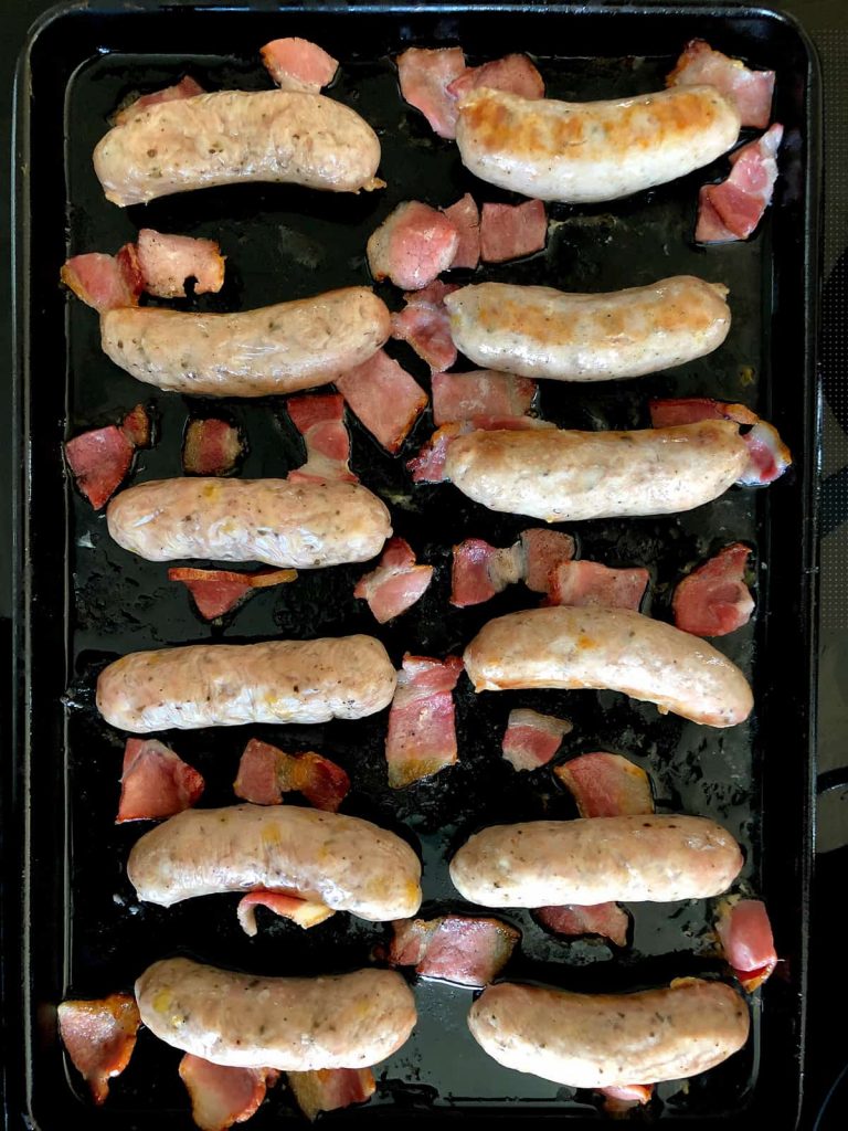 Sausages and pieces of bakon on a tray w