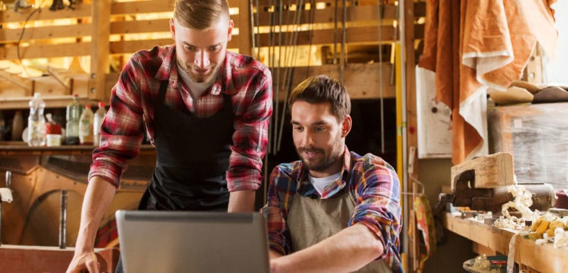 Handwerker zeigt anderem Handwerker blauarbeit.de auf einem Laptop