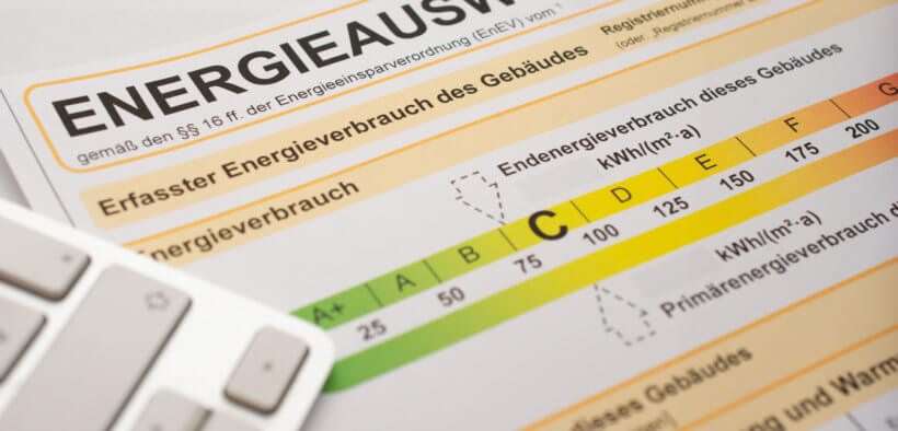 Ein Energieausweis und ein Laptop liegen auf einem Tisch