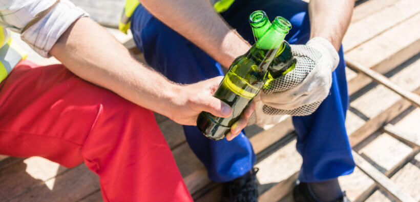 Zwei Handwerker trinken Alkohol bei der Arbeit.