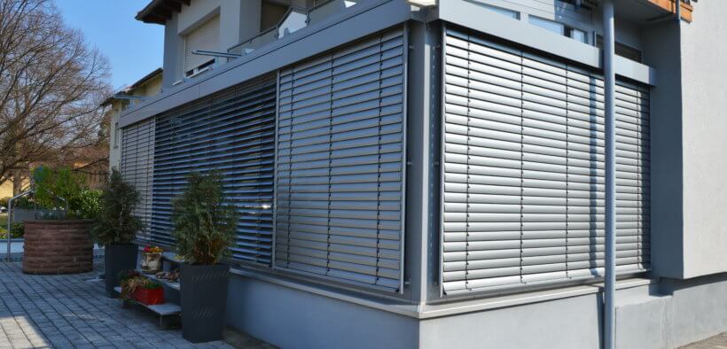 Verglaster Wintergarten mit elektrischen Rollläden als Beschattung an einem Wohnhaus