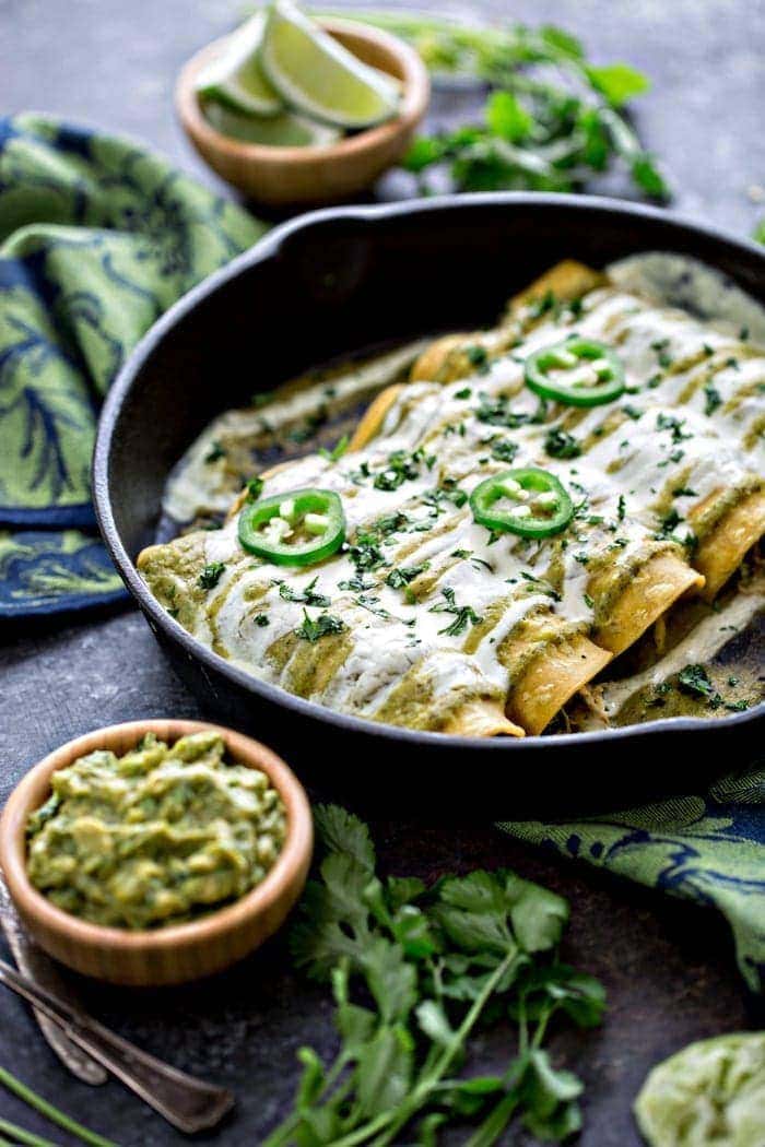 Chicken, Black Bean, and Spinach Enchiladas with Tomatillo Enchilada Sauce in cast iron skillet