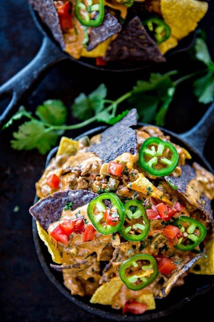 bowl of tortilla chips topped with crock pot queso and garnishes