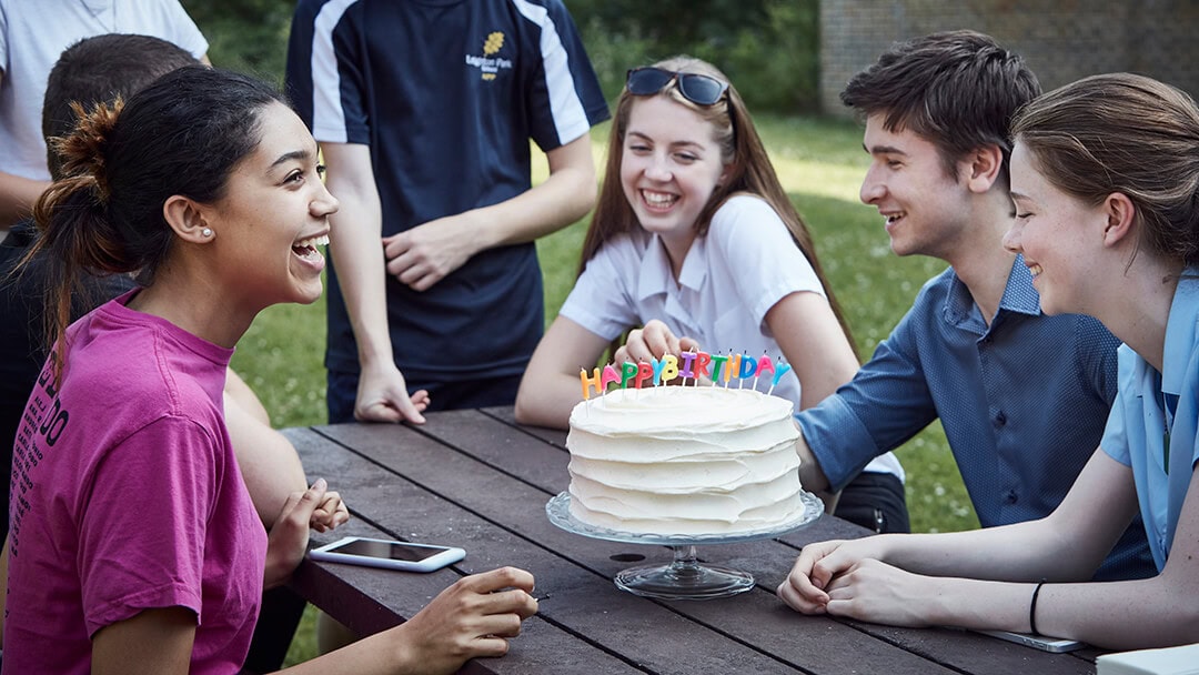 A group of student celebrating a birthday with a cake