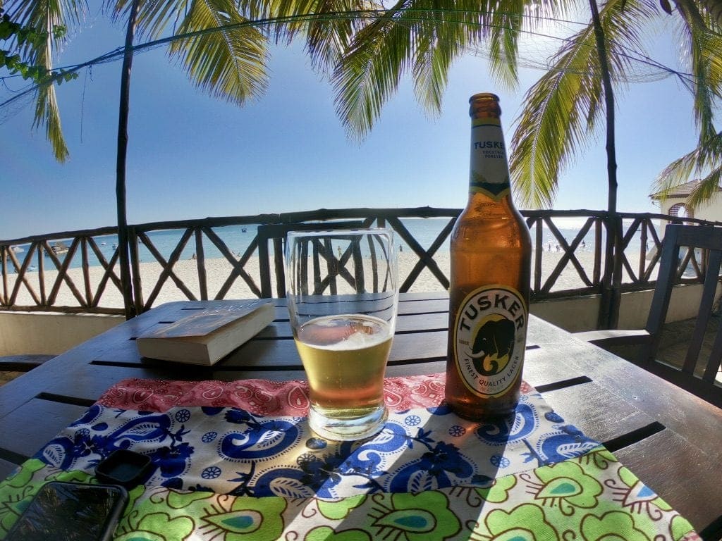 Una bottiglia e un bicchiere su un tavolo in spiaggia a Stone Town