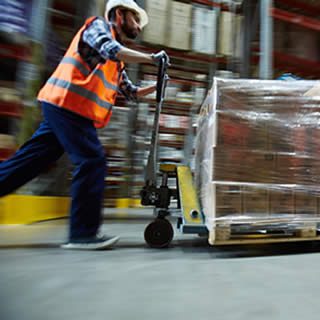 soldeur qui pousse rapidement un charriot elevateur contenant des cartons de produits rachetés suite à un sinistre de transport
