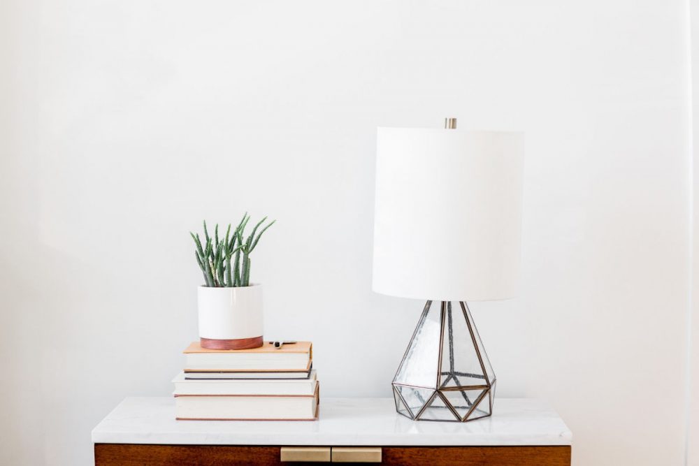 simple side table with modern lamp, stack of books, and plant