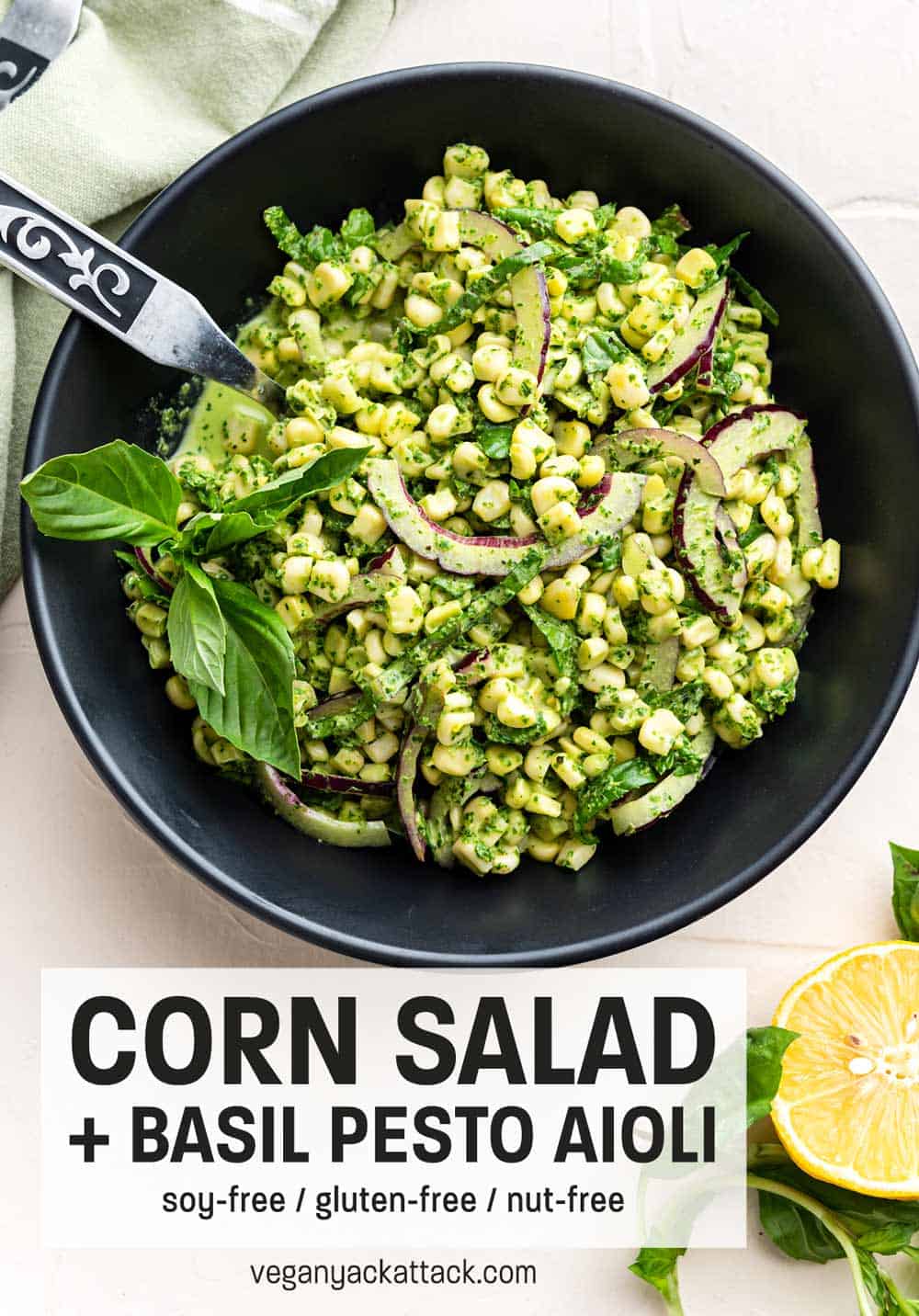 Large black bowl filled with Summer corn salad and basil pesto aioli with tongs and linen nearby
