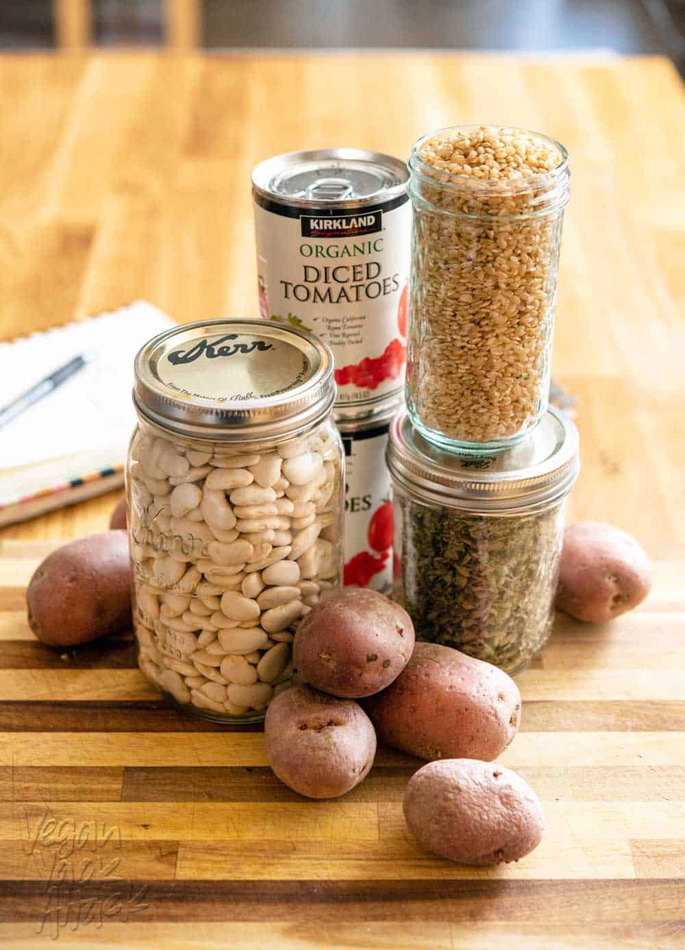 Picture of dried lima beans, red potatoes, canned tomatoes and rice, on a cutting board