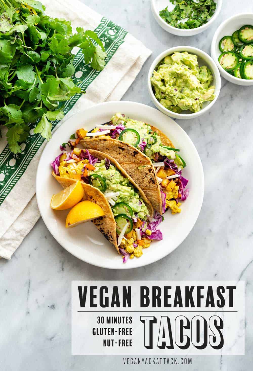 An image of tacos plated, on a marble table with assorted toppings near it, text reading "vegan breakfast tacos"
