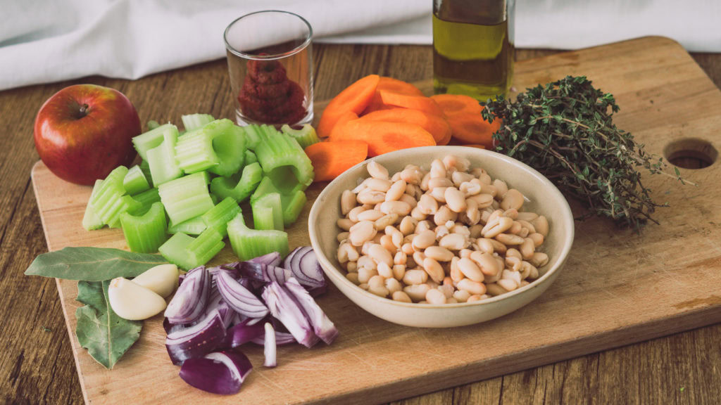 Gehacktes Gemüse für eine griechische Bohnensuppe auf einem großen Holzbrett