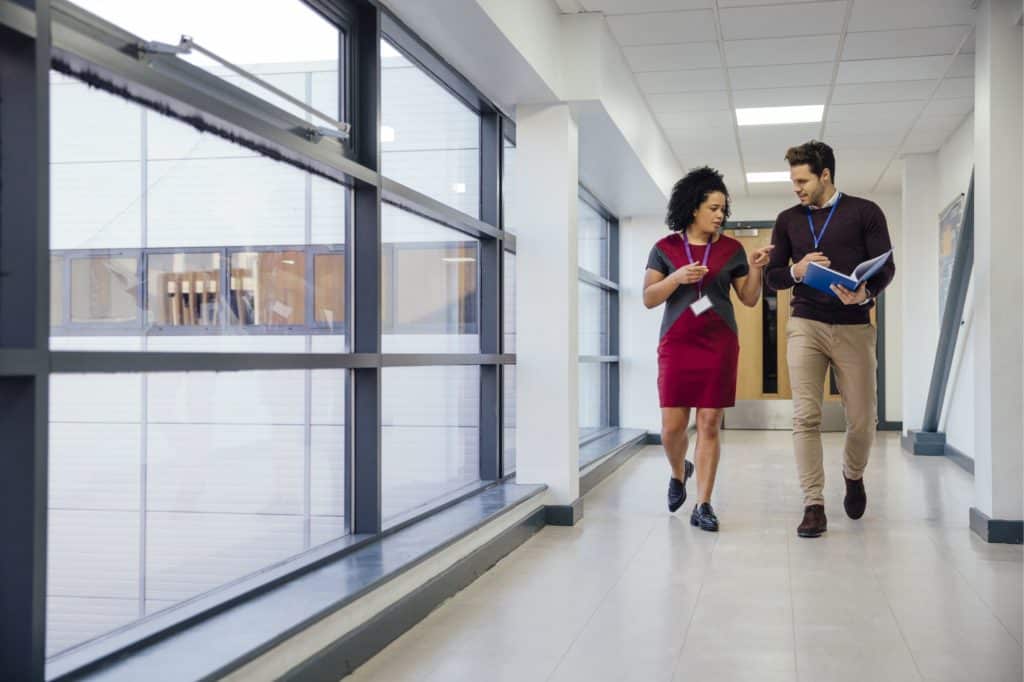 Two teachers talking while walking down a hall.