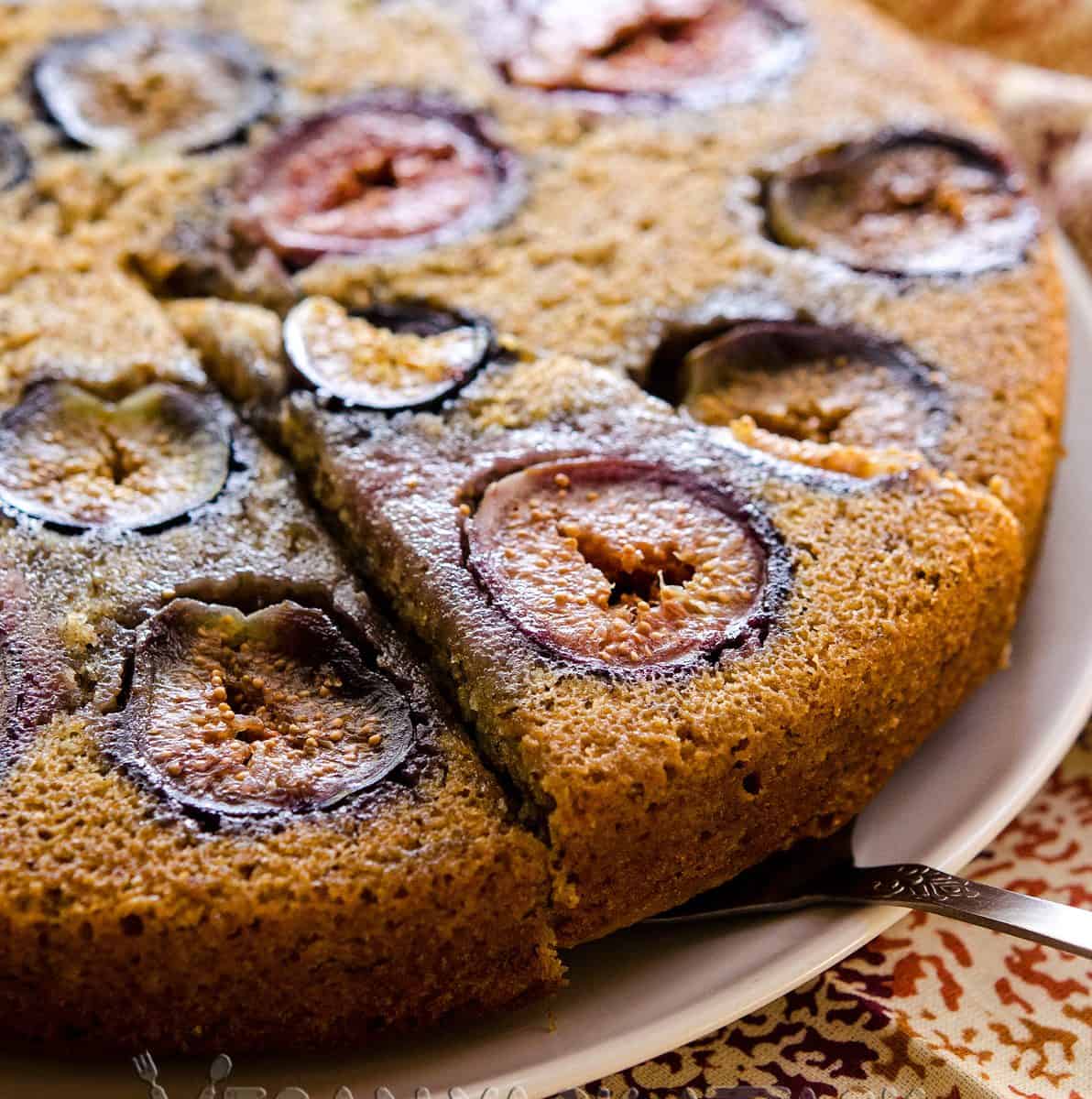 A simple vanilla cake with figs baked into it, with a slice being cut out