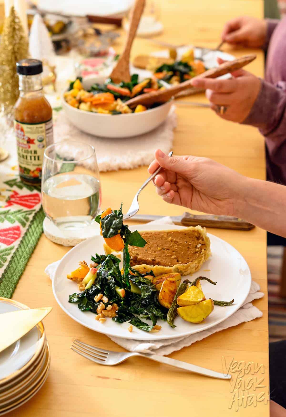 An adult eating salad off of a plate in a holiday dinner setting