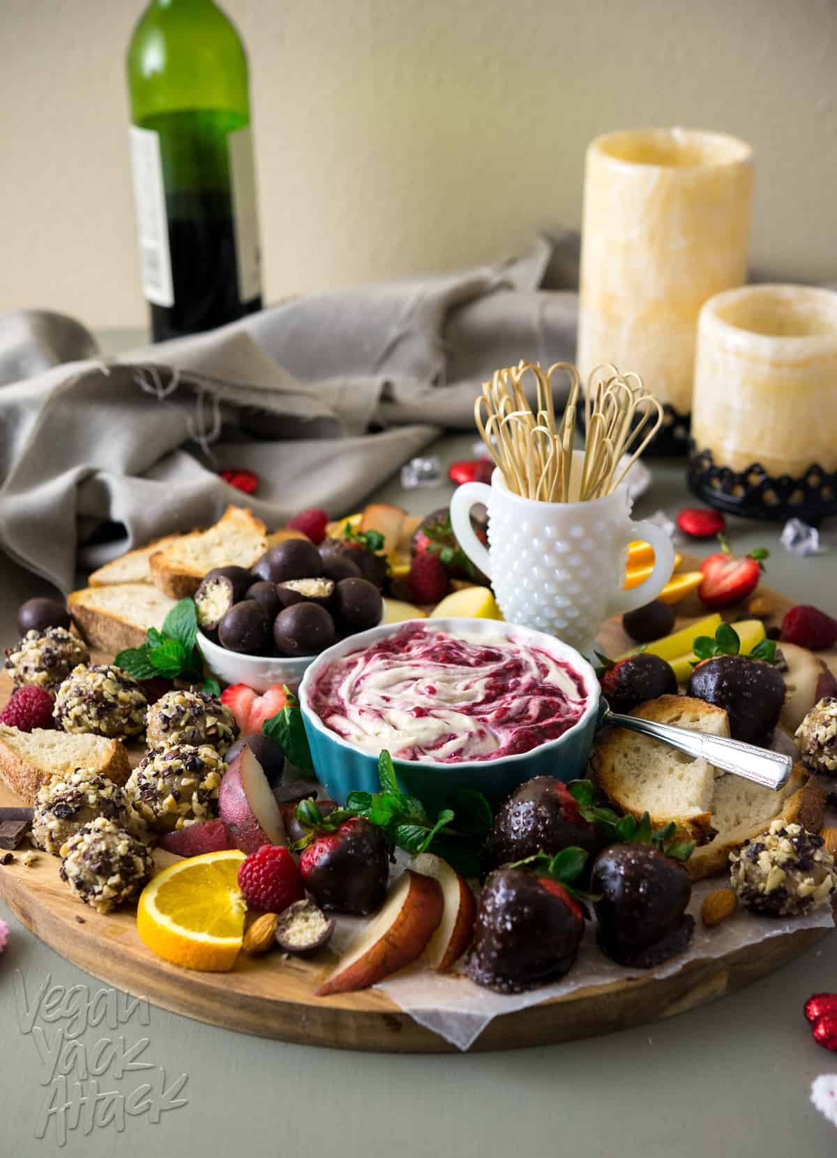 Image of elaborate dessert platter, featuring vegan sweets, raspberry merlot creme fraiche, with wine and candles in the background