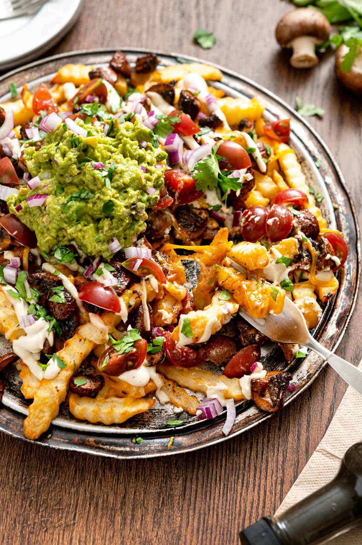 Close up shot of a platter of vegan mushroom asado fries on a wood table
