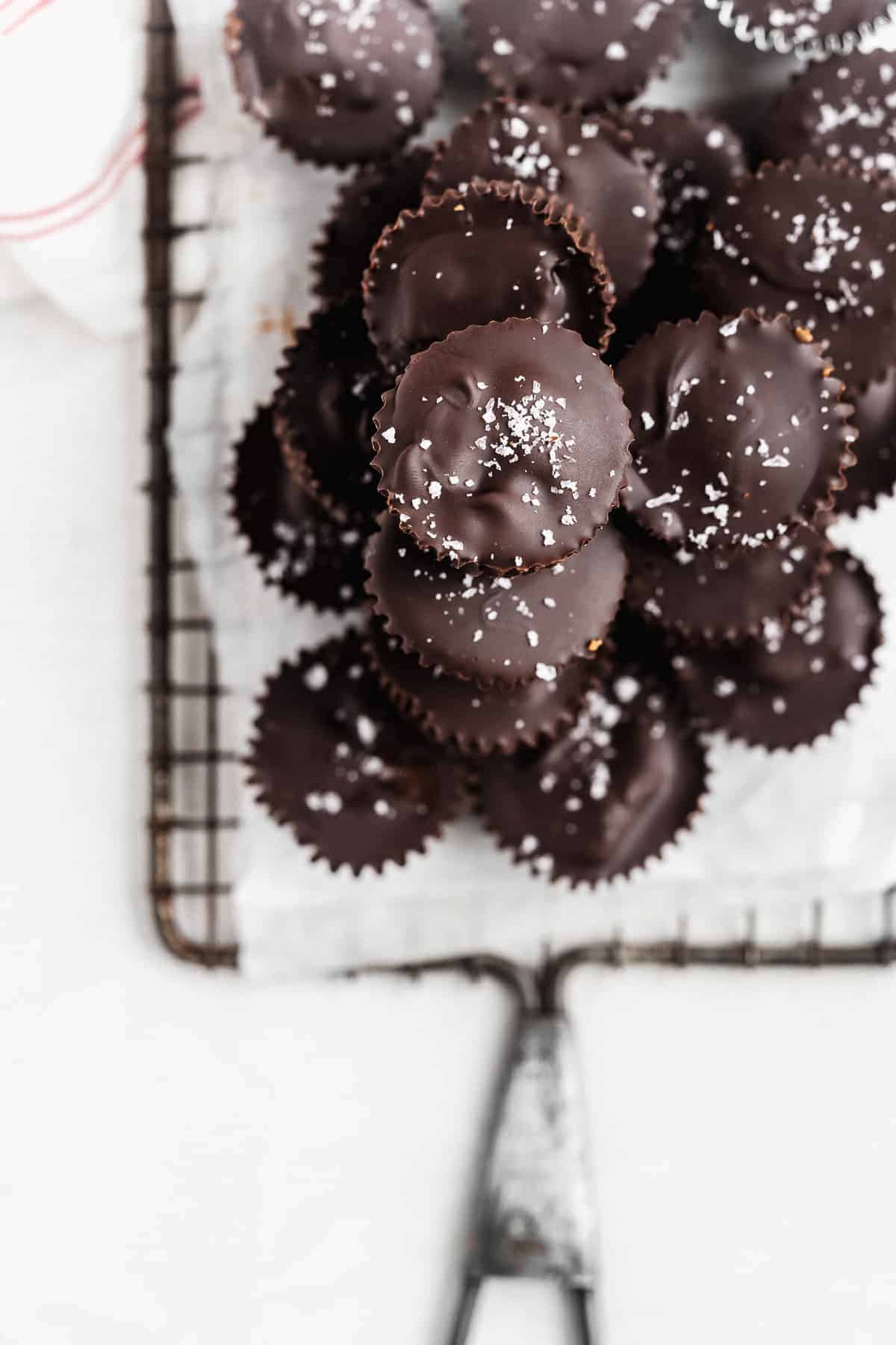 Chocolate pumpkin butter cups piled on a small wire rack with sea salt on top.