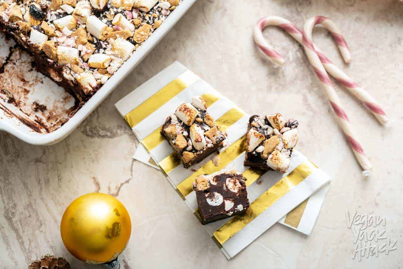 Pieces of vegan peppermint s'mores fudge cut out of the dish and on a napkin