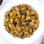 indian style pepper chicken in a bowl, along with some coarse black pepper on the side