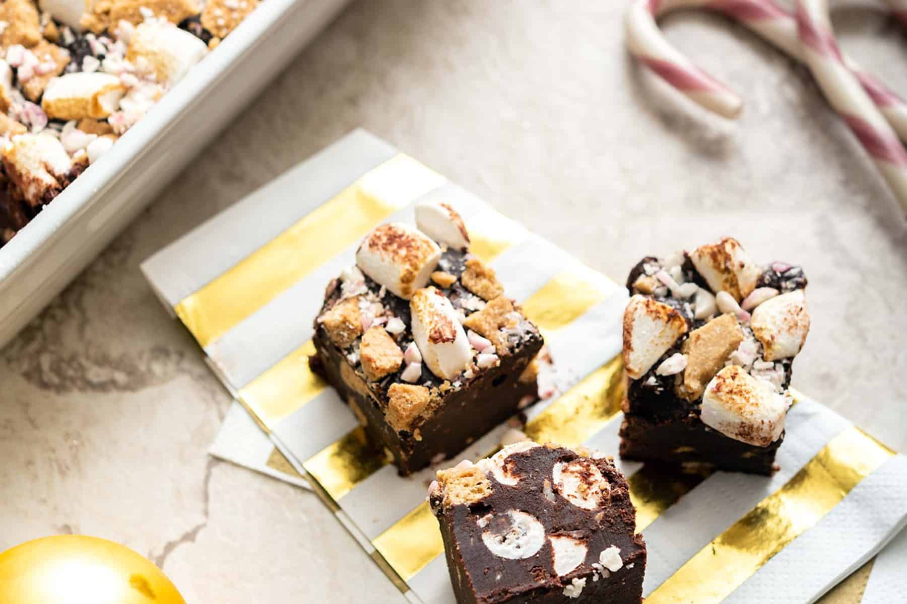 Pieces of vegan peppermint s'mores fudge cut out of the dish and on a napkin