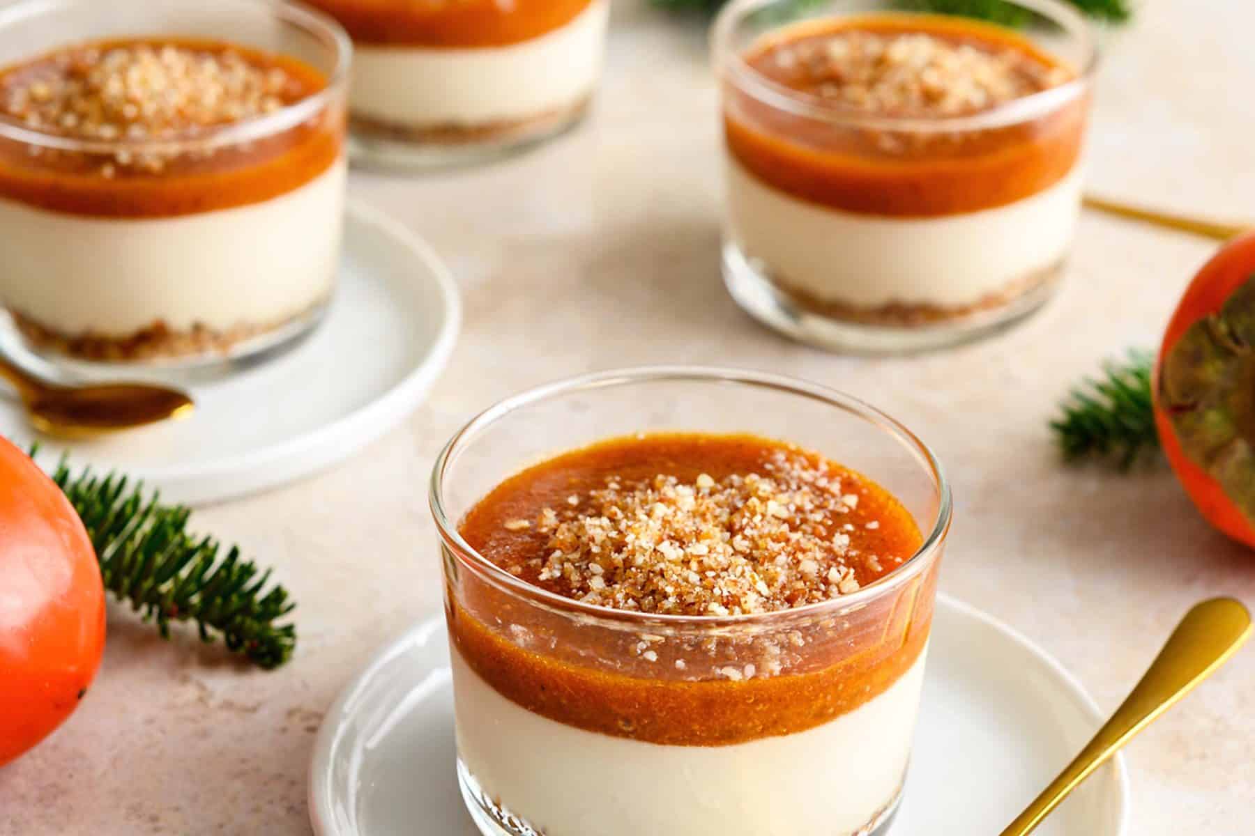 Persimmon cheesecake in a glass, on a white saucer with gold spoon