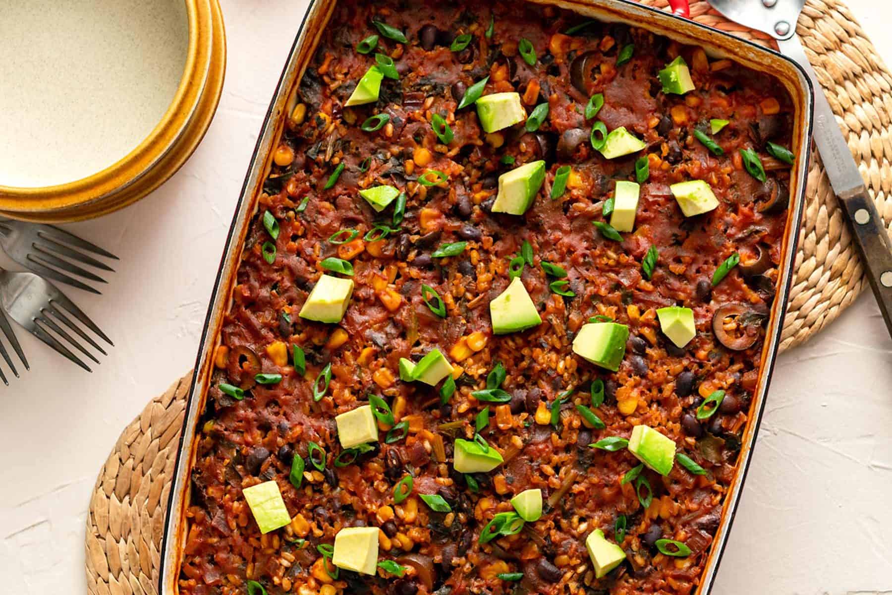 Image of chipotle brown rice bake in a red casserole dish on a beige background
