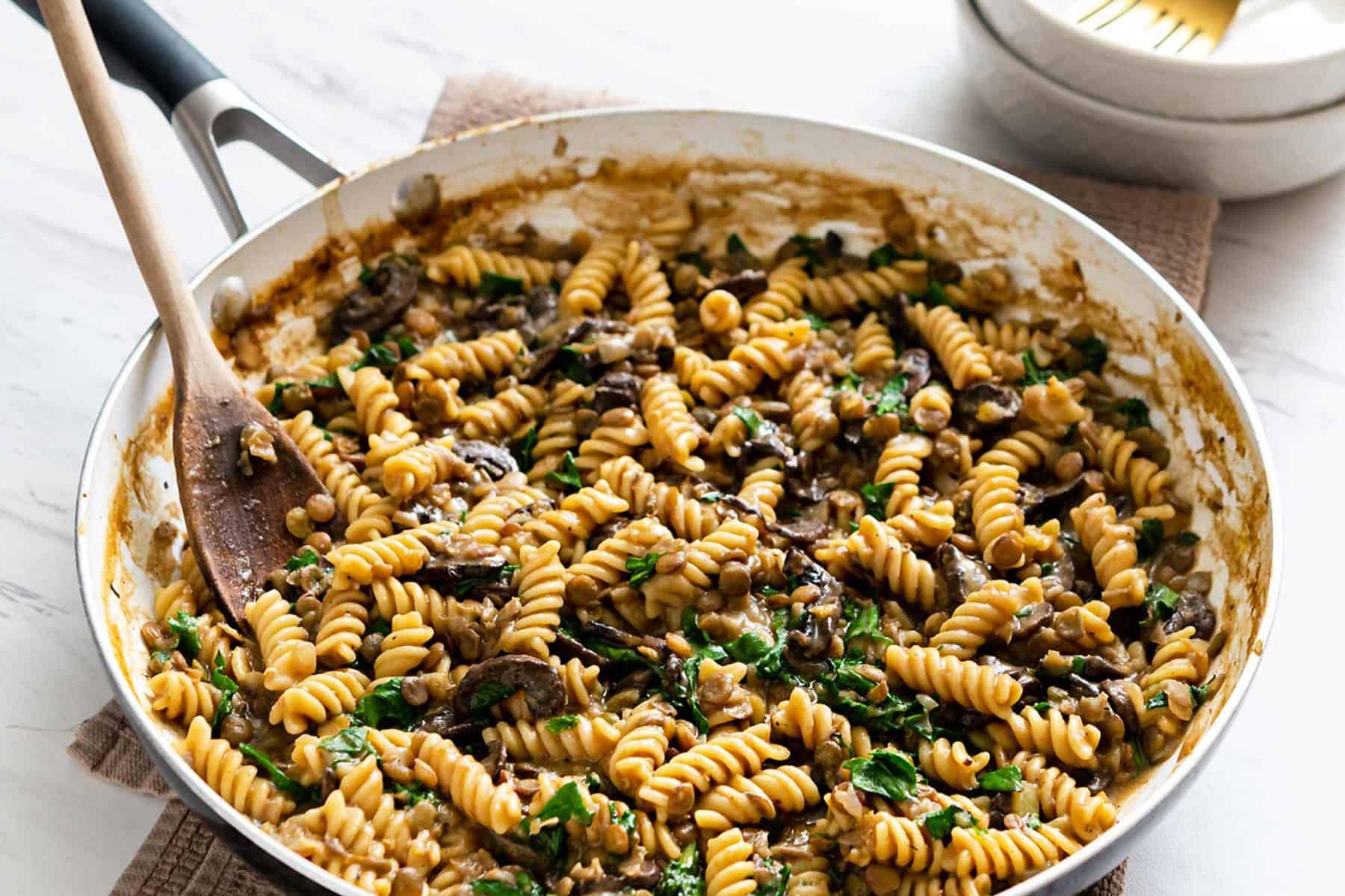 Image of one-pot lentil mushroom pasta in a large pan sitting on a towel