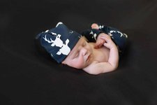 baby sleeping, grabbing foot, navy blue deer hat and pants