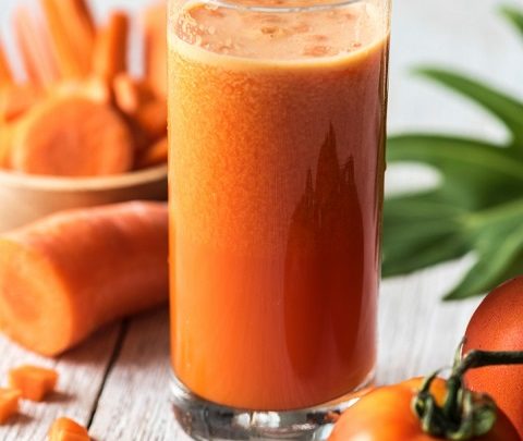 A glass of raw fresh juice with tomatoes and carrots