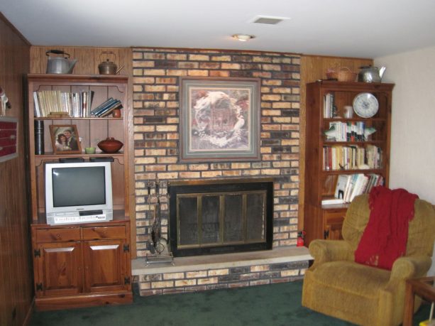 traditional family room design with floor to ceiling brick fireplace with wooden shelves on left and right sides