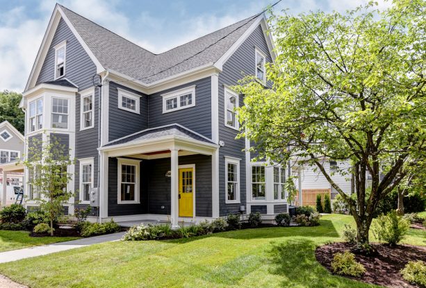 a transitional home exterior with dark grey paint, white trim, and yellow front door