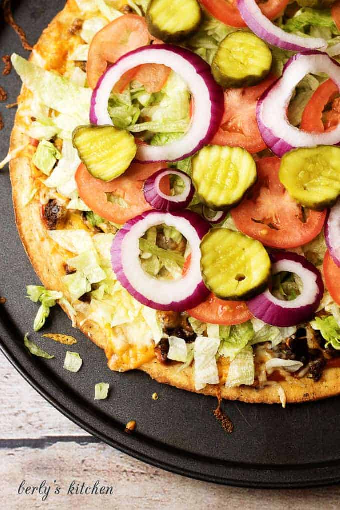 The Works Cheeseburger Pizza is a simple to prepare recipe loaded with all the fixings, including lettuce, tomatoes, pickles, and onions.