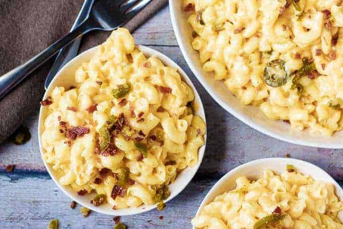 Ariel view of Instant Pot Mac and Cheese topped with bacon and jalapenos in three bowls with two forks.