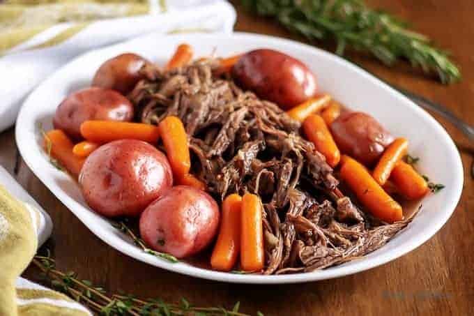 The finished Instant pot pot roast surrounded by cooked carrots and potatoes.