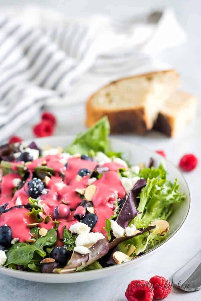 The salad dressing over a of Spring mix topped with feta cheese.