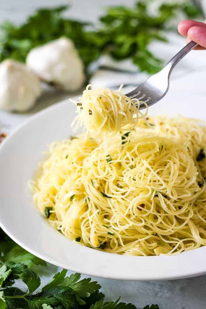 The noodles being lifted out of the bowl with a fork.