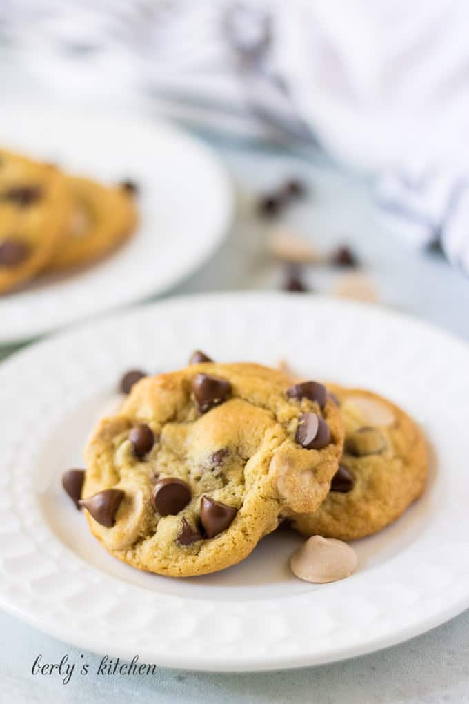 Three caramel chocolate chip cookies on a small white plate.