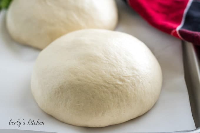 Two balls of homemade Publix pizza dough on a sheet pan.